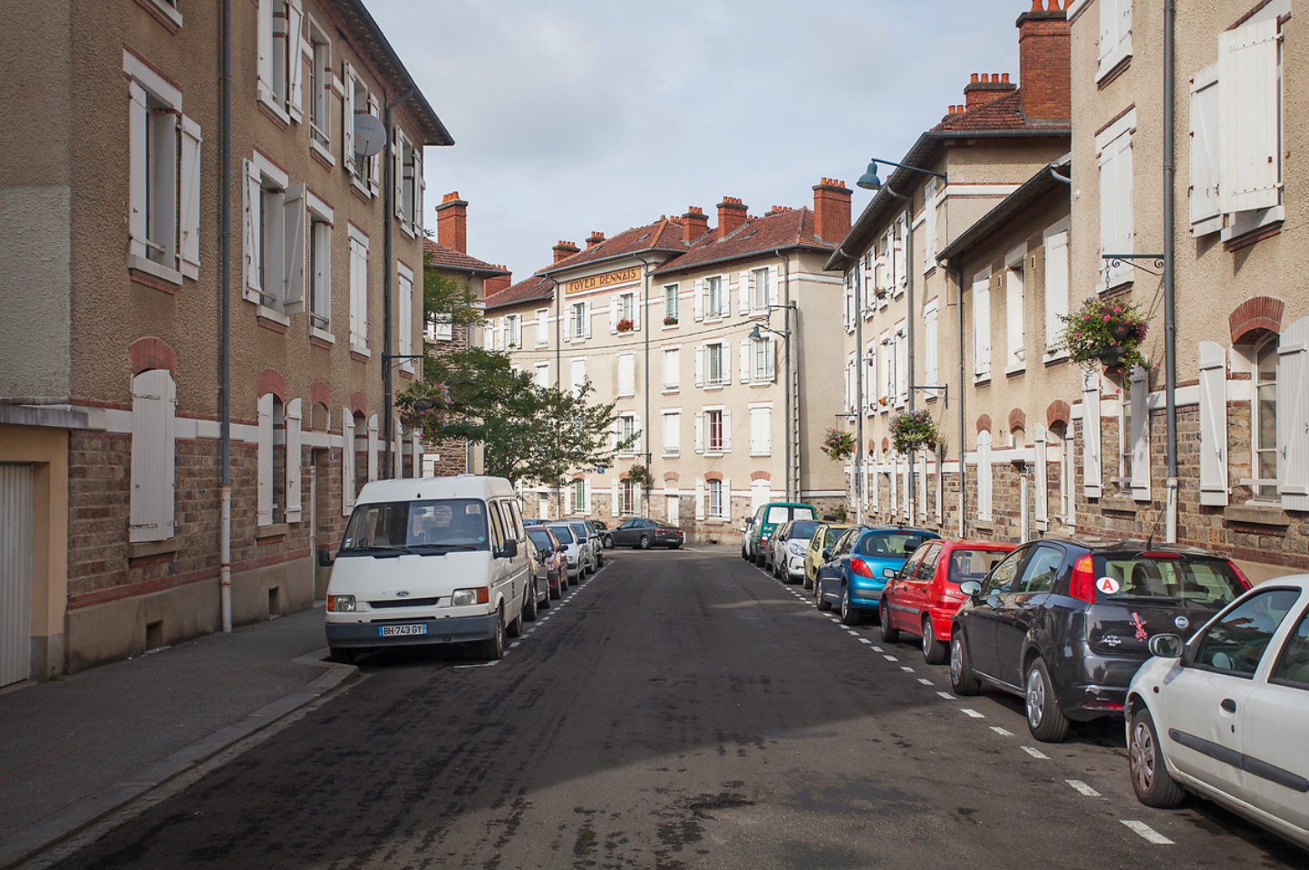 Une rue en centre ville avec des voitures stationnées et des immeubles