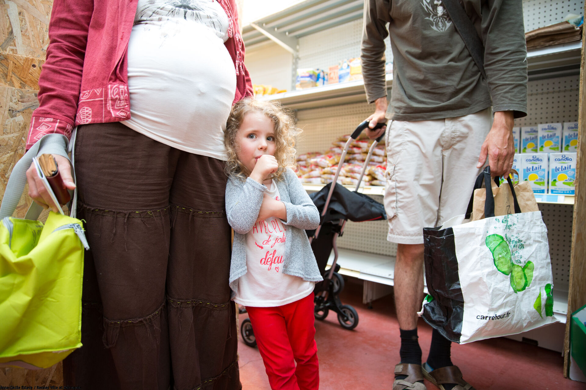 Une petite fille suce son pouce et une femme enceinte