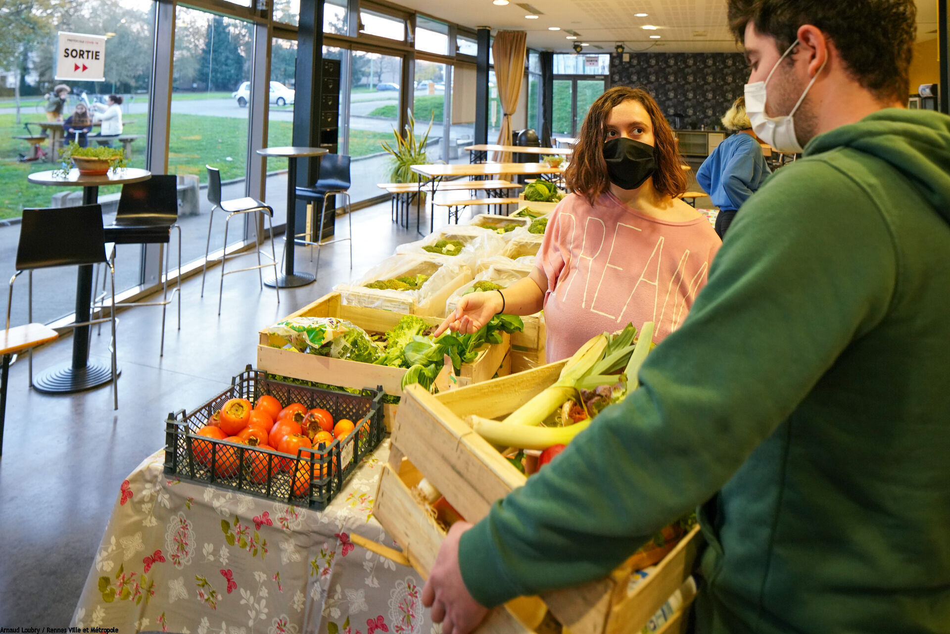 Bénévole transportant une cagette de légumes sur une table